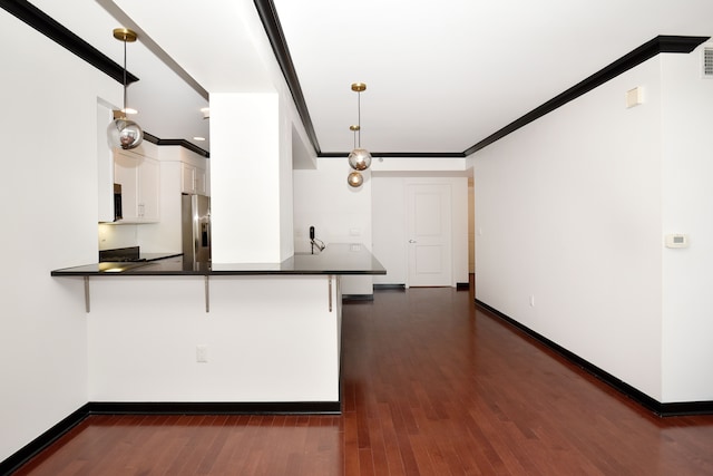 kitchen with a kitchen bar, kitchen peninsula, white cabinetry, and pendant lighting