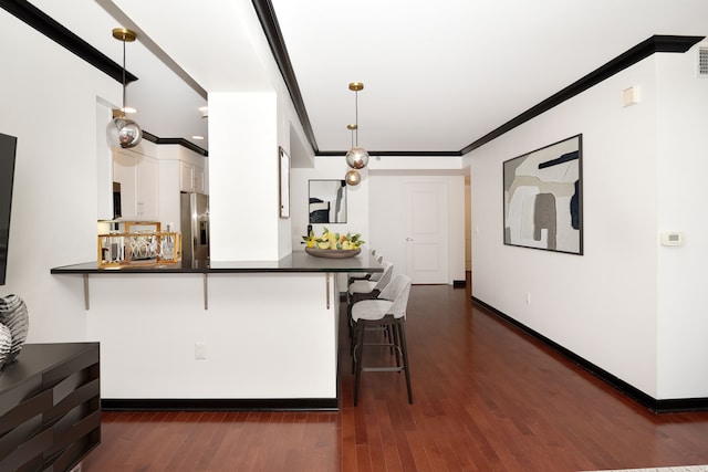 kitchen featuring kitchen peninsula, stainless steel appliances, decorative light fixtures, white cabinets, and a breakfast bar area