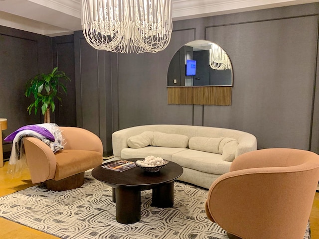 living room with wood-type flooring, an inviting chandelier, and ornamental molding