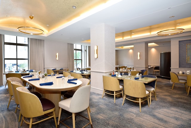 dining space with a tray ceiling and dark colored carpet