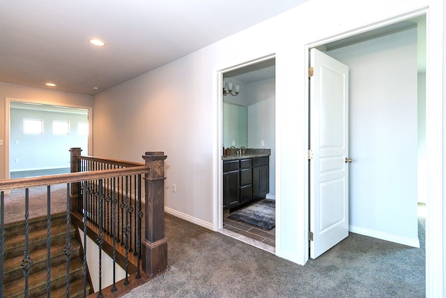 hallway featuring dark colored carpet and sink