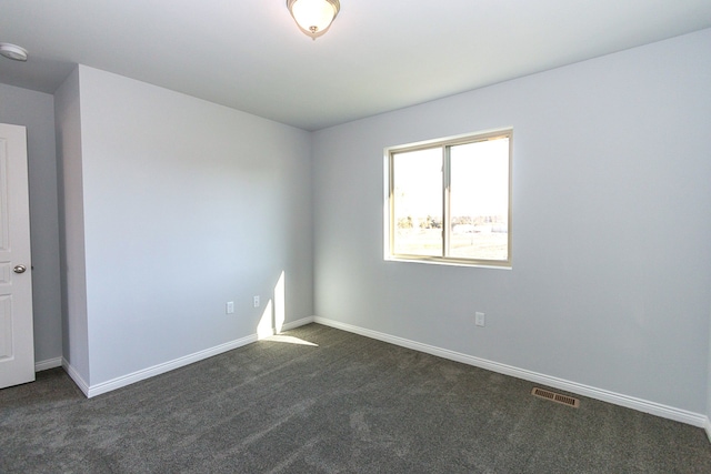 spare room featuring dark colored carpet