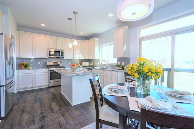 kitchen featuring hanging light fixtures, decorative backsplash, a kitchen island, dark hardwood / wood-style flooring, and stainless steel appliances