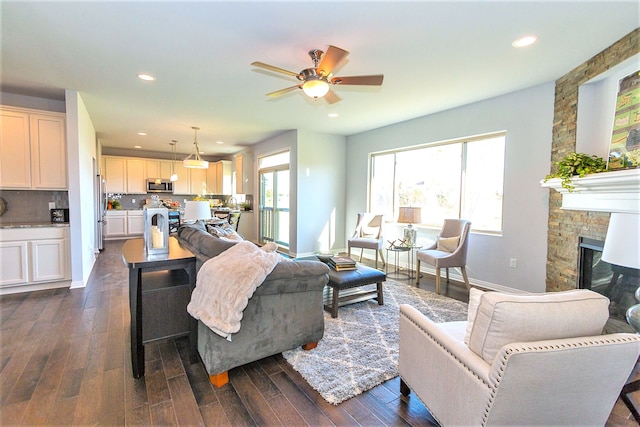 living room with dark hardwood / wood-style floors, ceiling fan, and a fireplace