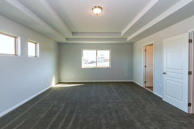 empty room featuring dark carpet and a raised ceiling