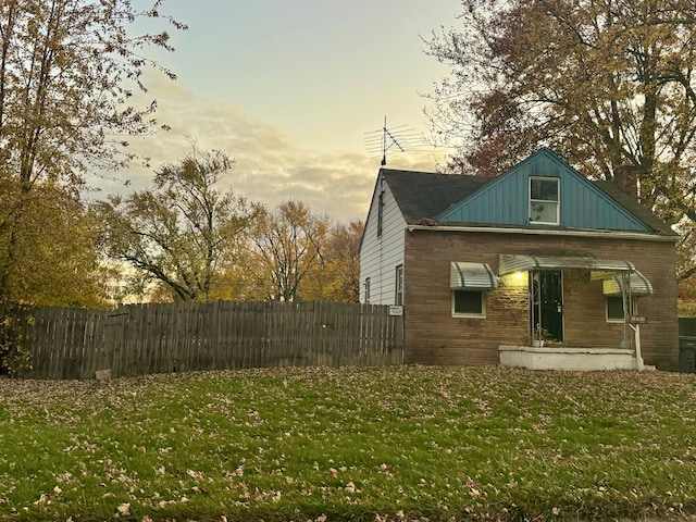 property exterior at dusk featuring a lawn