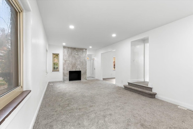 unfurnished living room with plenty of natural light, light colored carpet, and a premium fireplace