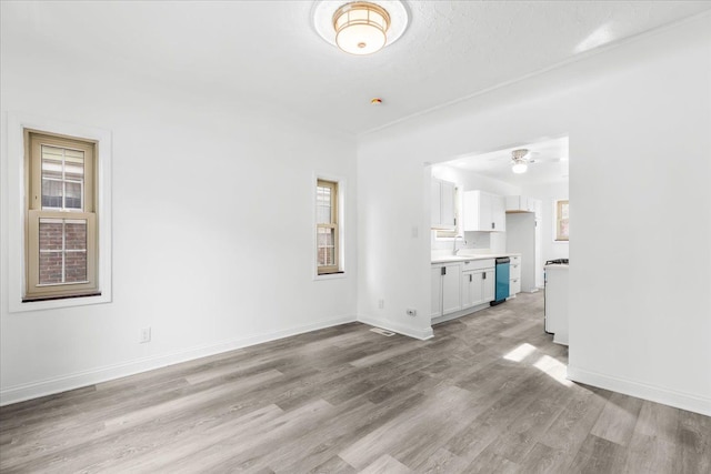 unfurnished living room with a textured ceiling, light hardwood / wood-style floors, ceiling fan, and sink