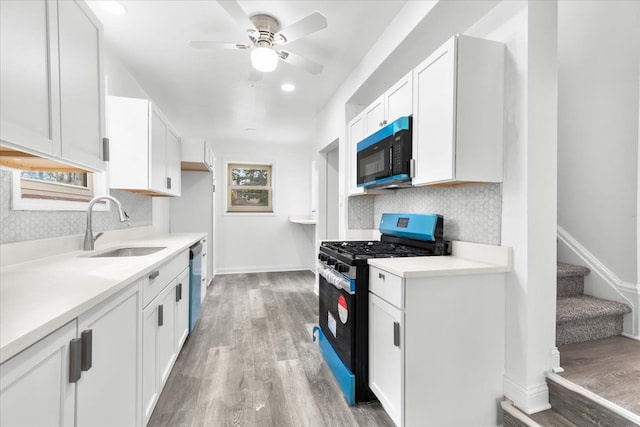 kitchen with gas stove, sink, dishwasher, white cabinets, and light hardwood / wood-style floors