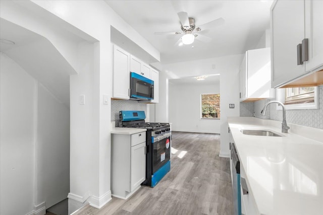 kitchen with backsplash, sink, black appliances, light hardwood / wood-style floors, and white cabinetry