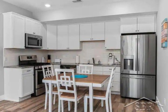 kitchen featuring stainless steel appliances, white cabinetry, hardwood / wood-style flooring, and sink