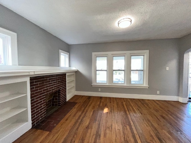 unfurnished living room with dark hardwood / wood-style floors, a fireplace, and a textured ceiling