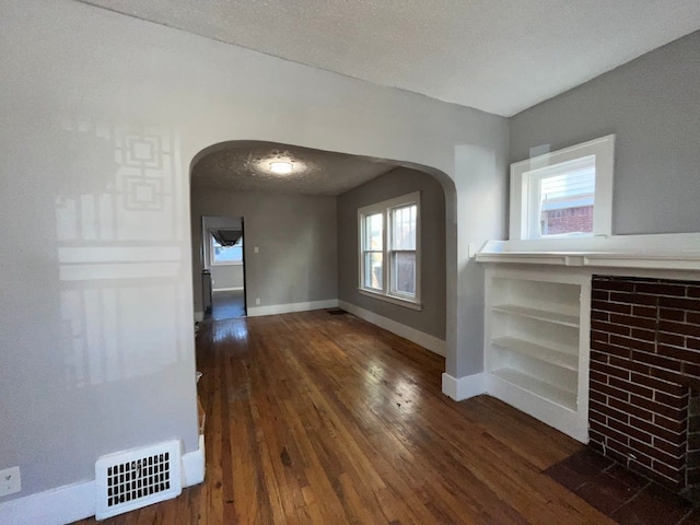 unfurnished dining area featuring a textured ceiling and dark hardwood / wood-style floors