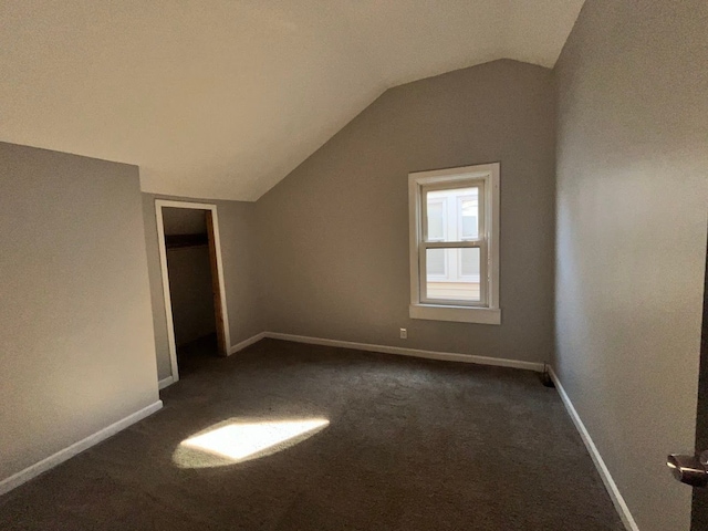 bonus room with dark colored carpet and vaulted ceiling