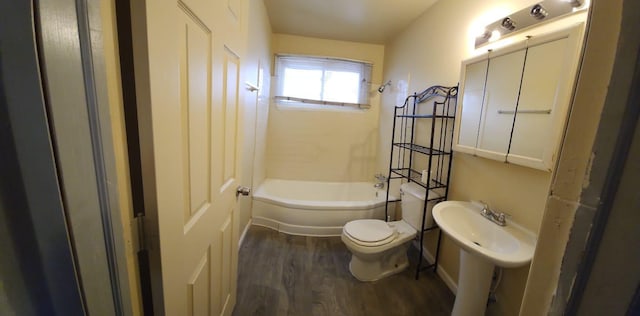 bathroom featuring hardwood / wood-style flooring, washtub / shower combination, and toilet