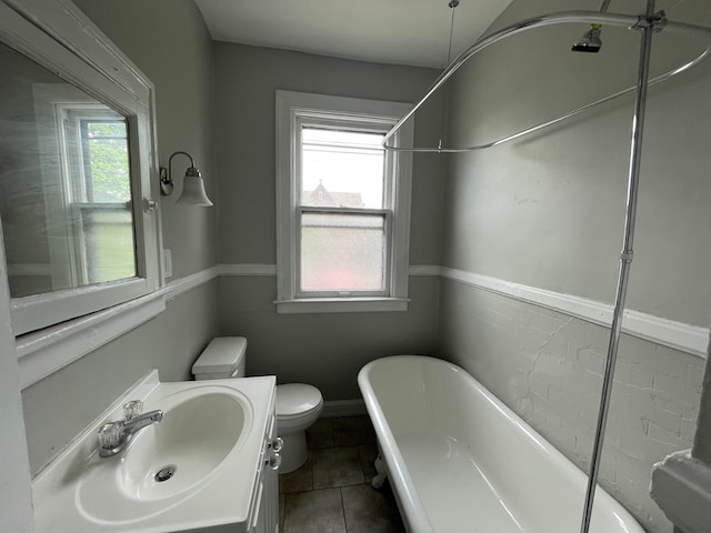 bathroom featuring tile patterned floors, a bathing tub, a healthy amount of sunlight, and toilet