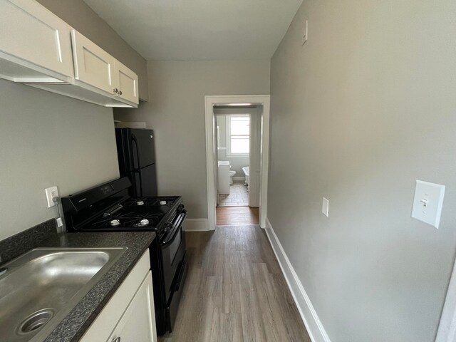 kitchen featuring black appliances, white cabinets, sink, and light hardwood / wood-style flooring