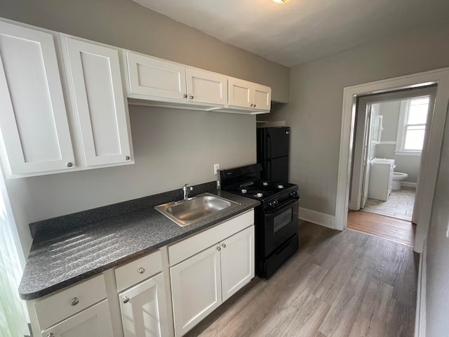 kitchen featuring sink, white cabinets, black appliances, and light wood-type flooring