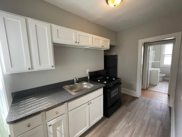 kitchen featuring black appliances, white cabinets, light wood-type flooring, and sink