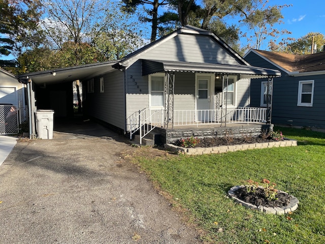 view of front of home featuring covered porch, a front lawn, and a carport