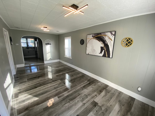 interior space with dark hardwood / wood-style floors, ornamental molding, and wooden walls