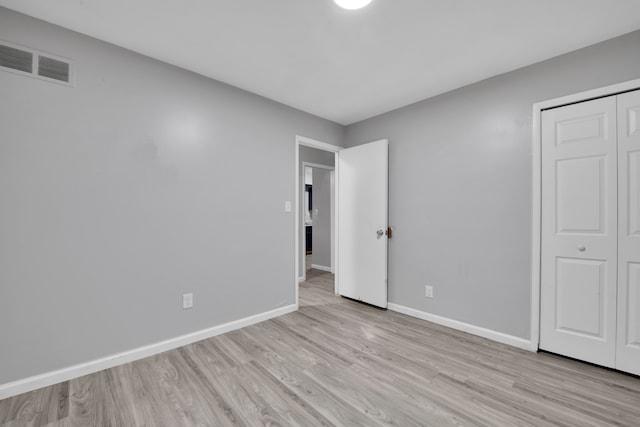 unfurnished bedroom with a closet and light wood-type flooring