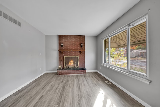 unfurnished living room with hardwood / wood-style flooring and a brick fireplace