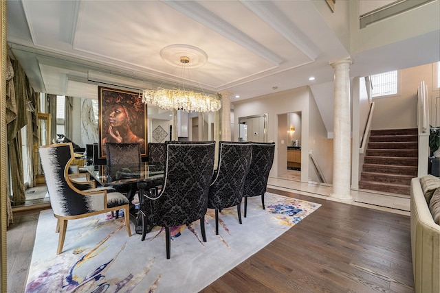 dining space with ornate columns, crown molding, hardwood / wood-style floors, and an inviting chandelier