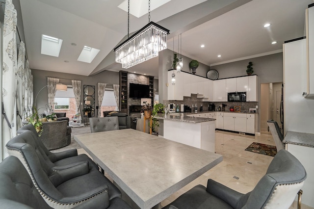 dining area with an inviting chandelier, lofted ceiling with skylight, and crown molding