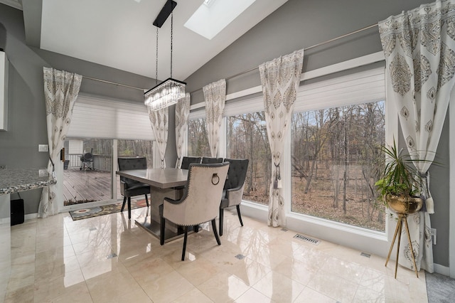 dining room with lofted ceiling with skylight and an inviting chandelier