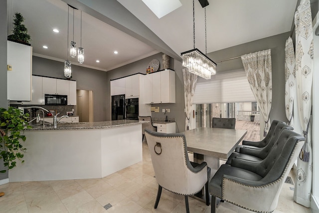 dining space with a skylight, sink, an inviting chandelier, and ornamental molding