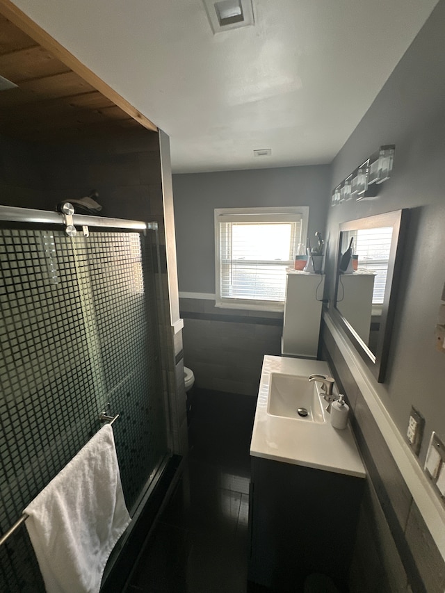 bathroom with tile patterned floors, vanity, toilet, and a shower with door