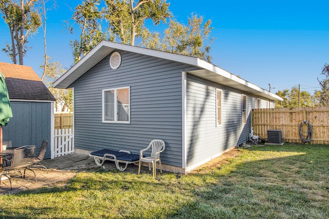 rear view of house with a lawn, central AC, and a shed