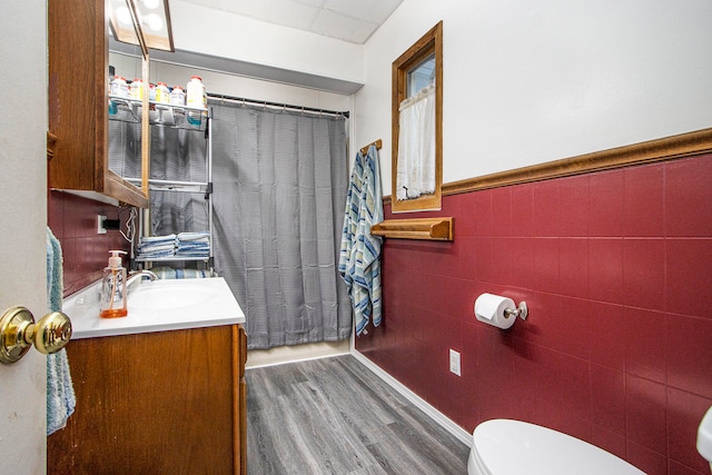 bathroom with vanity, toilet, wood-type flooring, and tile walls