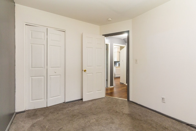 unfurnished bedroom with dark carpet and a closet