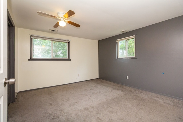 spare room with ceiling fan, a healthy amount of sunlight, and light carpet