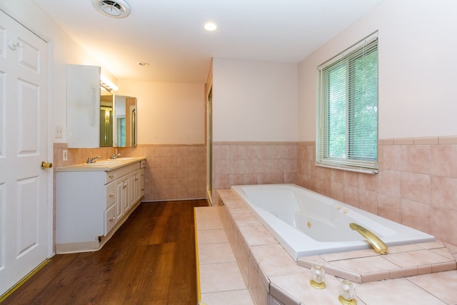 bathroom featuring vanity, wood-type flooring, and tiled bath