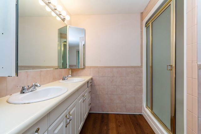 bathroom with vanity, hardwood / wood-style flooring, tile walls, and a shower with door