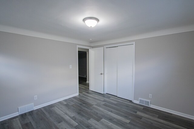 unfurnished bedroom featuring dark hardwood / wood-style flooring and a closet