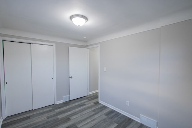 unfurnished bedroom featuring dark hardwood / wood-style flooring and a closet