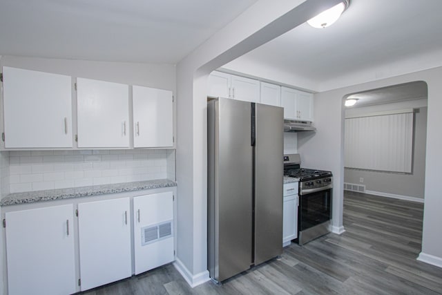 kitchen featuring white cabinets, decorative backsplash, wood-type flooring, and appliances with stainless steel finishes