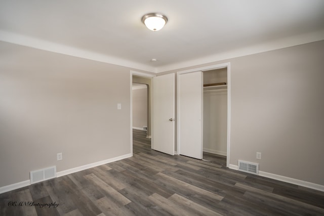 unfurnished bedroom featuring a closet, dark wood finished floors, visible vents, and baseboards