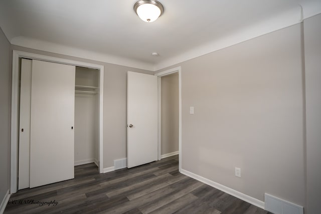 unfurnished bedroom with baseboards, a closet, visible vents, and dark wood-style flooring