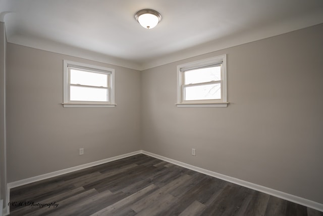 spare room featuring plenty of natural light, baseboards, and dark wood finished floors