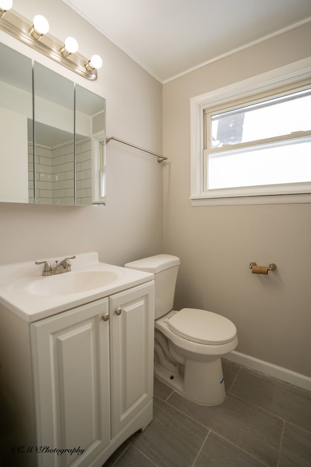 bathroom with tile patterned flooring, toilet, vanity, baseboards, and ornamental molding