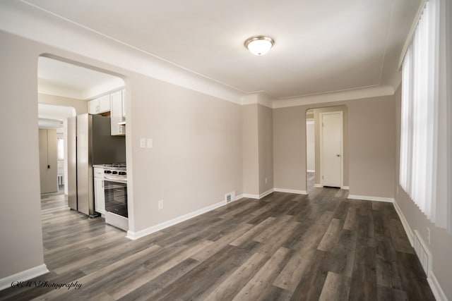 unfurnished room featuring dark wood-type flooring, visible vents, and baseboards