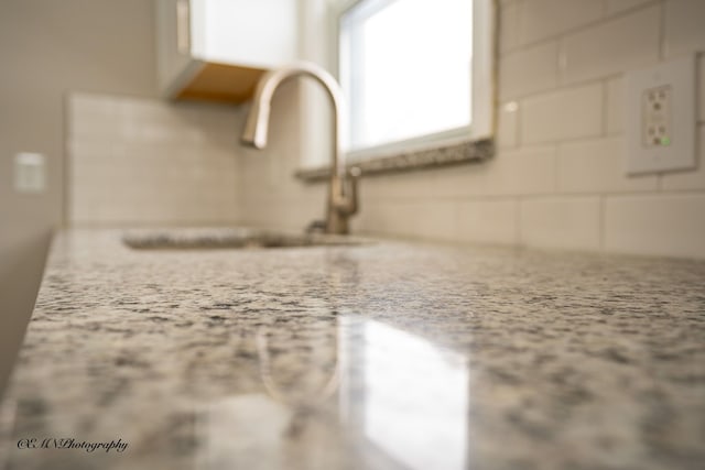 details featuring a sink and light stone countertops