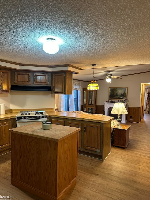 kitchen featuring hanging light fixtures, a center island, butcher block countertops, and white range with gas cooktop