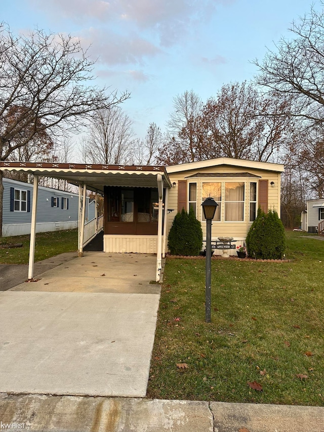 manufactured / mobile home with a carport and a front yard