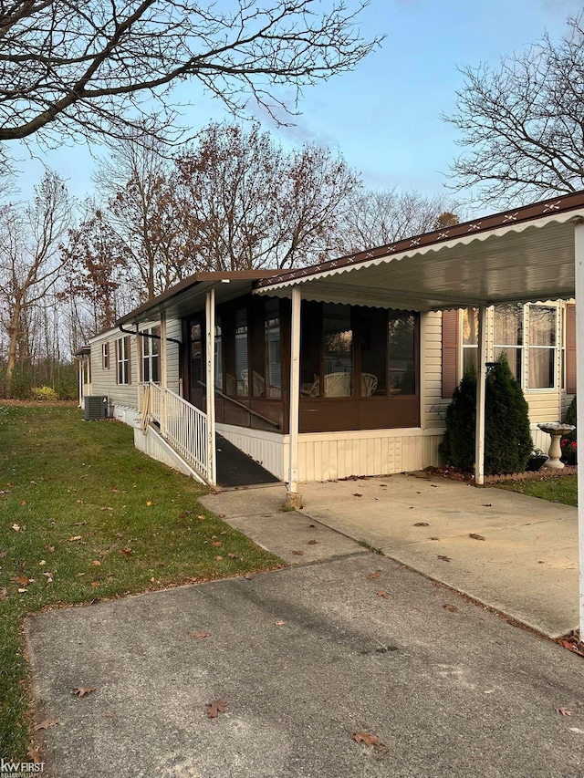 view of side of home with central AC, a sunroom, a yard, and a carport